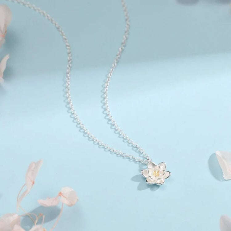Collier Fleur de Lotus en argent sur fond bleu avec ambiance poétique, chaîne fine et pendentif en forme de fleur délicate