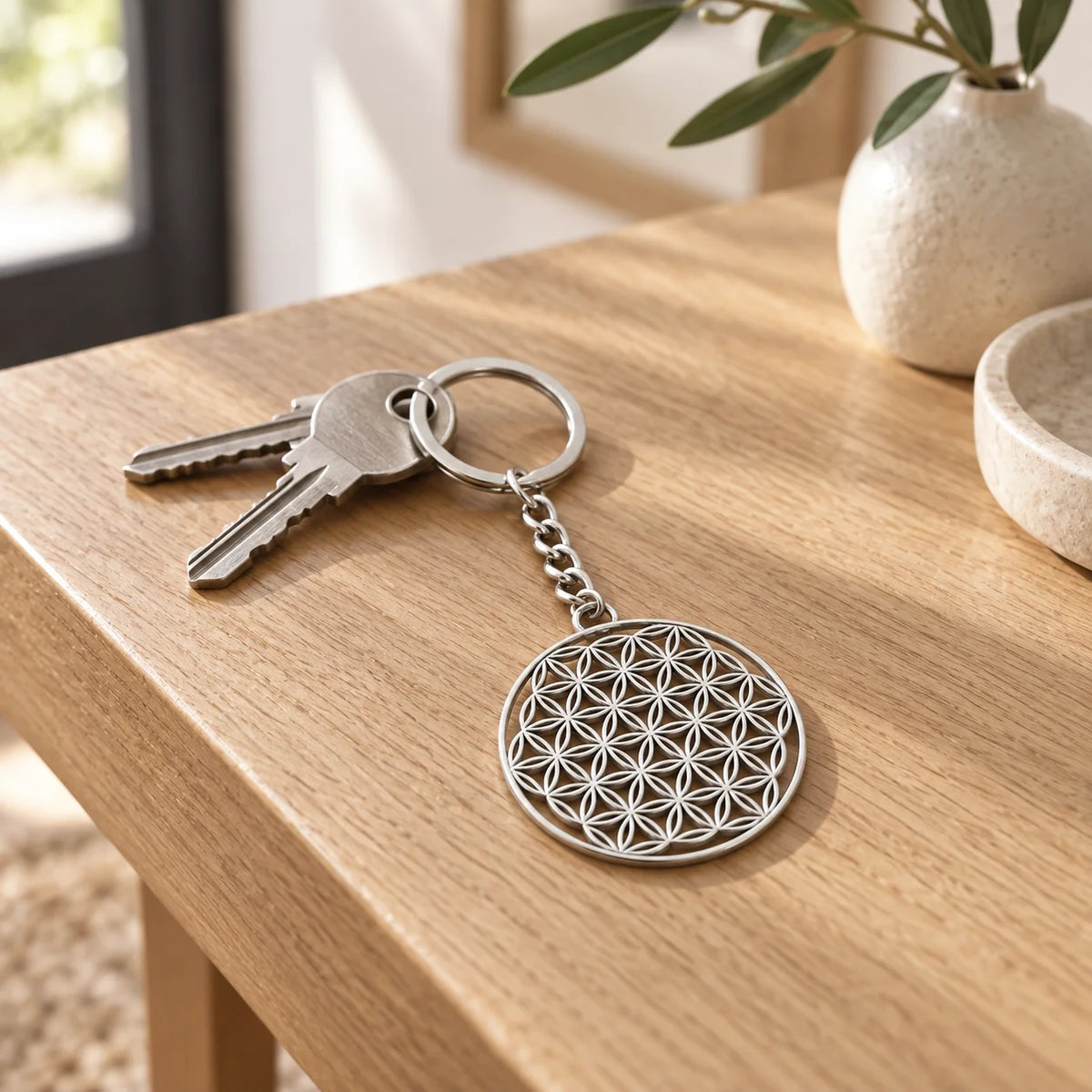 Porte-clé fleur de vie argenté avec des clés sur une console en bois