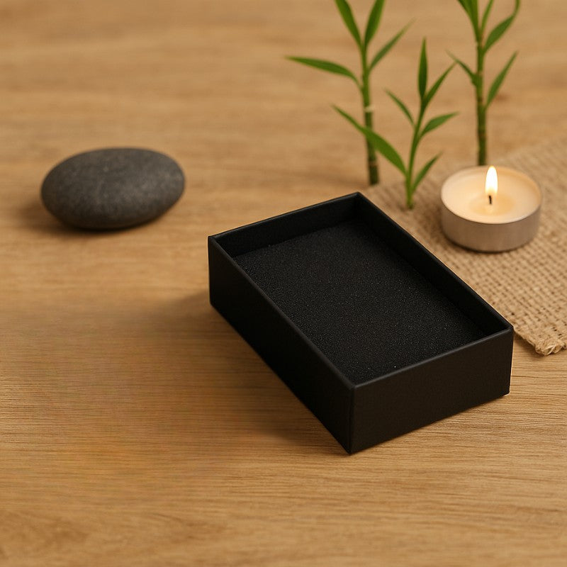 Boîte écrin noire ouverte pour bijou posée sur une surface en bois