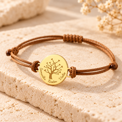 Bracelet arbre de vie personnalisé doré avec cordon marron ajustable, présenté sur un fond en pierre beige