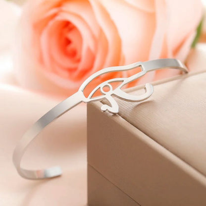 Bracelet Oeil d'Horus en argent reposant sur une boîte à bijoux, avec une rose en arrière-plan.