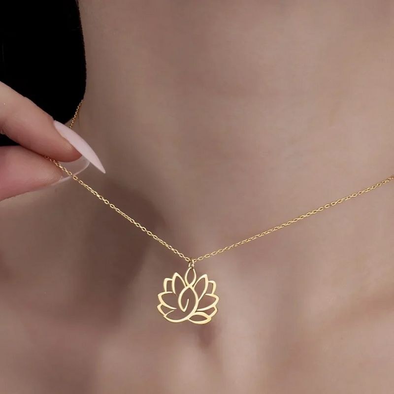 Collier Fleur de Lotus en or tenu par une femme, révélant la finesse et la beauté de son pendentif ajouré.