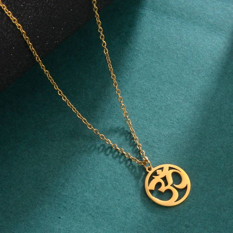 Collier avec pendentif Aum en or sur fond vert, mettant en valeur son design ajouré et son éclat raffiné