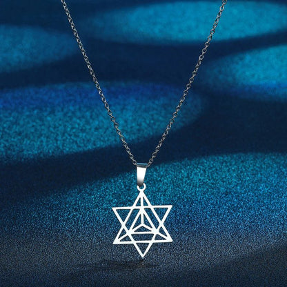 Pendentif Merkaba en argent sur fond bleu lumineux, un bijou puissant associant esthétique et spiritualité.