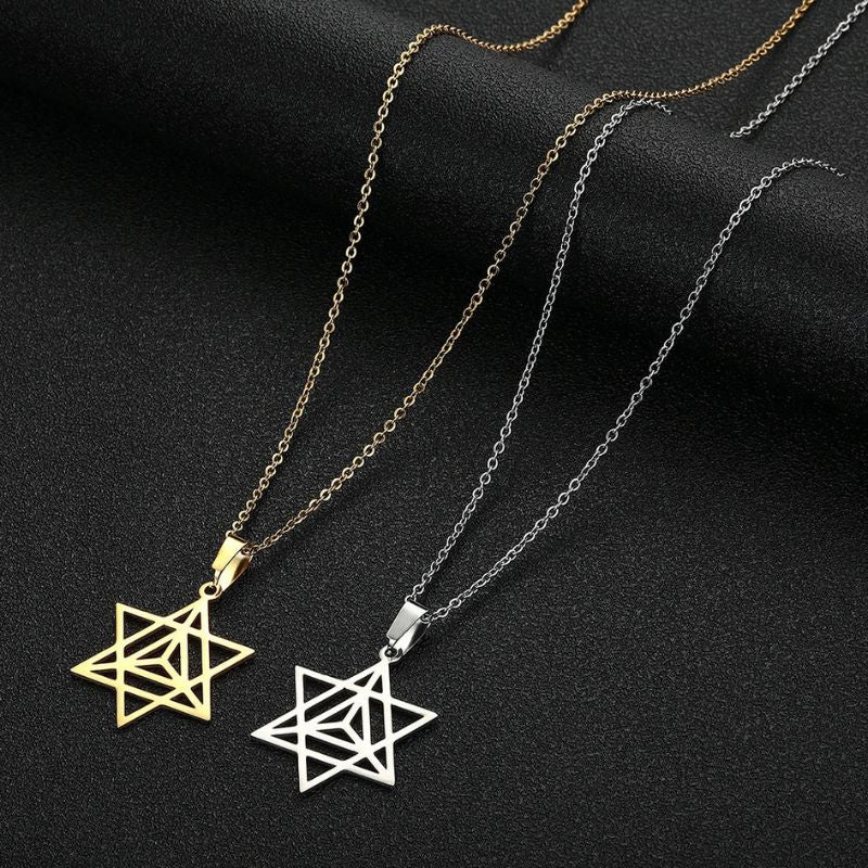 Duo de pendentifs Merkaba en or et en argent sur fond sombre, illustrant les deux variations du collier symbolique.