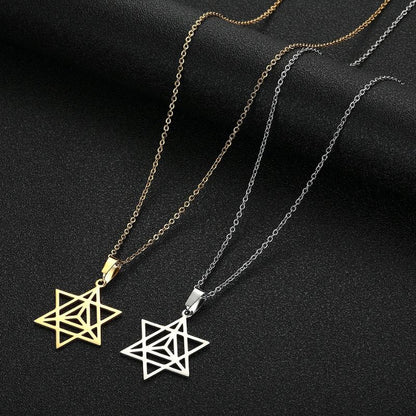 Duo de pendentifs Merkaba en or et en argent sur fond sombre, illustrant les deux variations du collier symbolique.
