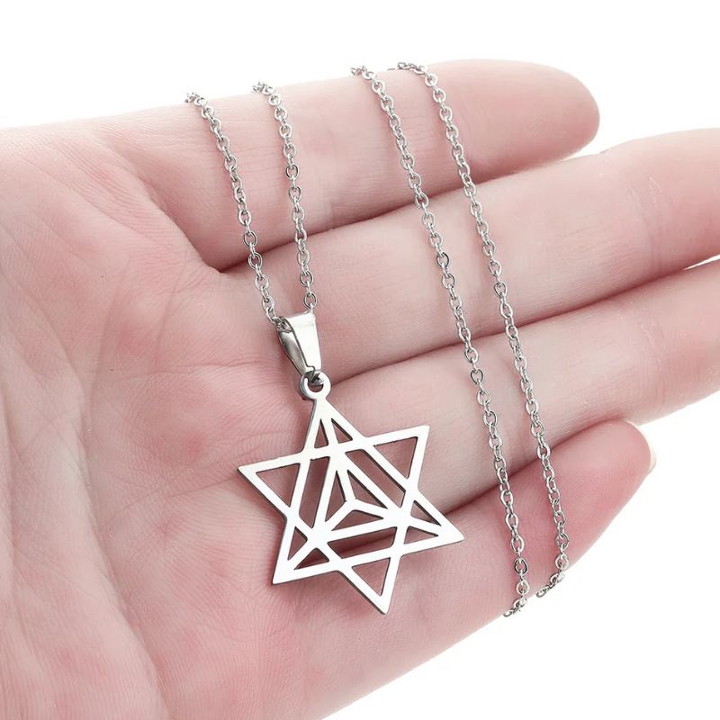 Collier Merkaba en argent tenu dans une main, montrant la finesse des détails et la taille idéale du pendentif.
