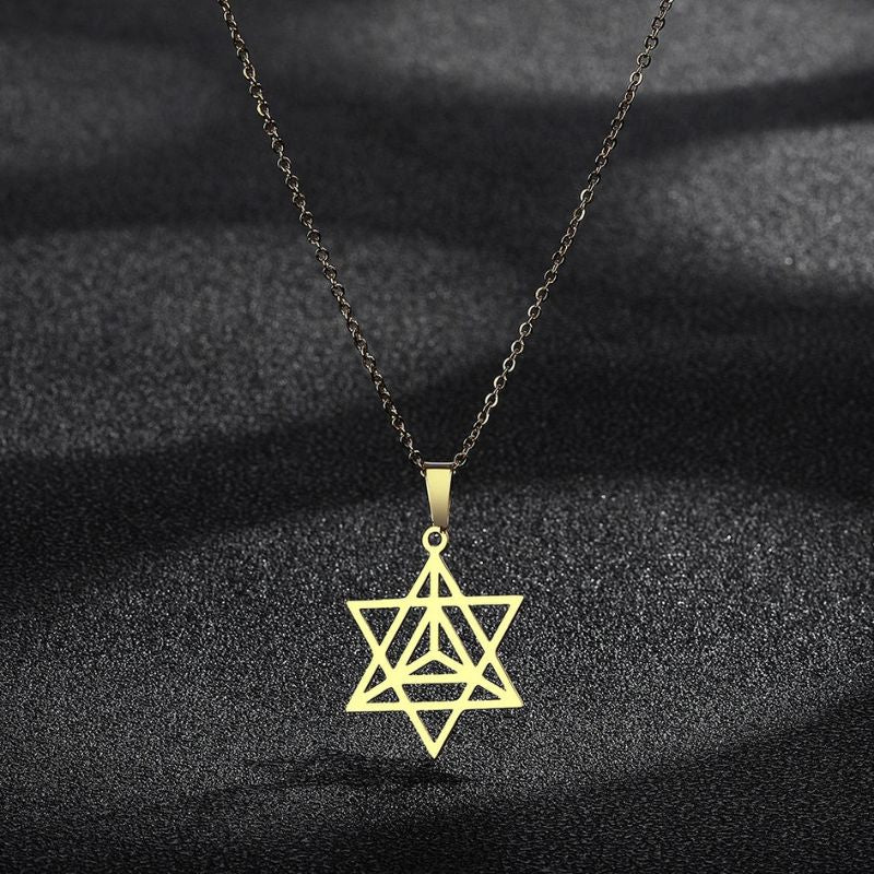 Collier Merkaba en or présenté sur un fond noir texturé, mettant en valeur la brillance et l'élégance du bijou spirituel.