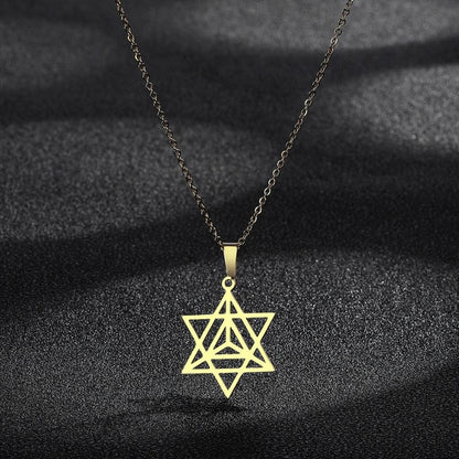 Collier Merkaba en or présenté sur un fond noir texturé, mettant en valeur la brillance et l'élégance du bijou spirituel.