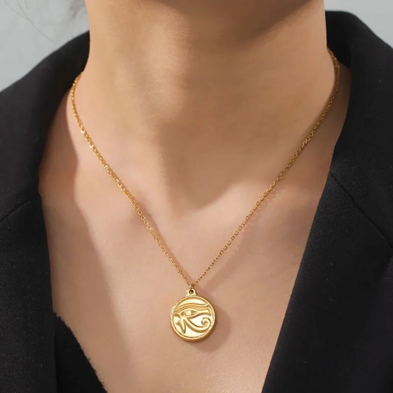 Pendentif Œil d'Horus en acier inoxydable argenté, porté par un modèle en tenue noire, mettant en valeur son design discret et protecteur.