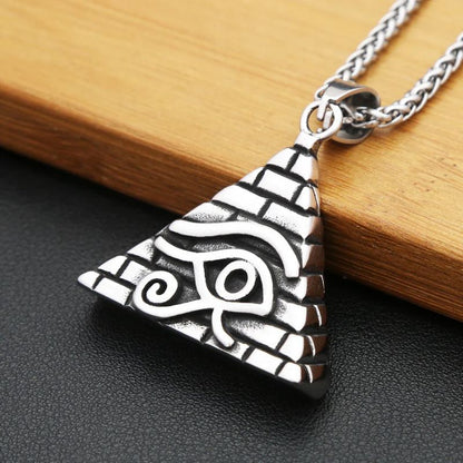 Collier avec pendentif Oeil d'Horus en argent posé sur une surface en bois, mettant en valeur son design pyramidal gravé de détails mystiques.