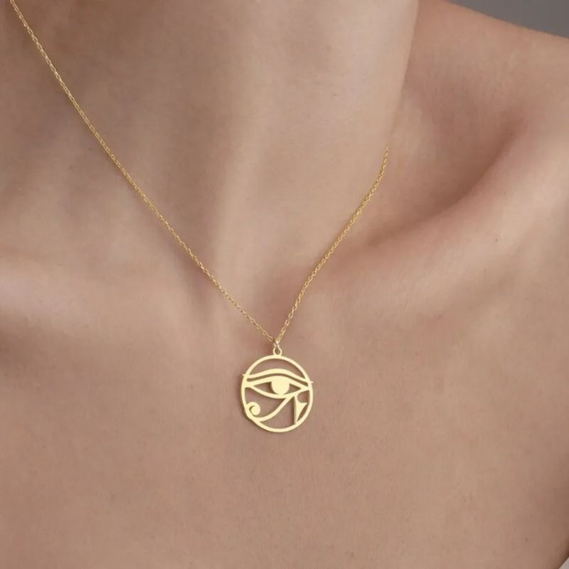 Collier Oeil d'Horus en or porté autour du cou d'une femme, mettant en valeur son éclat doré et son design finement ajouré.